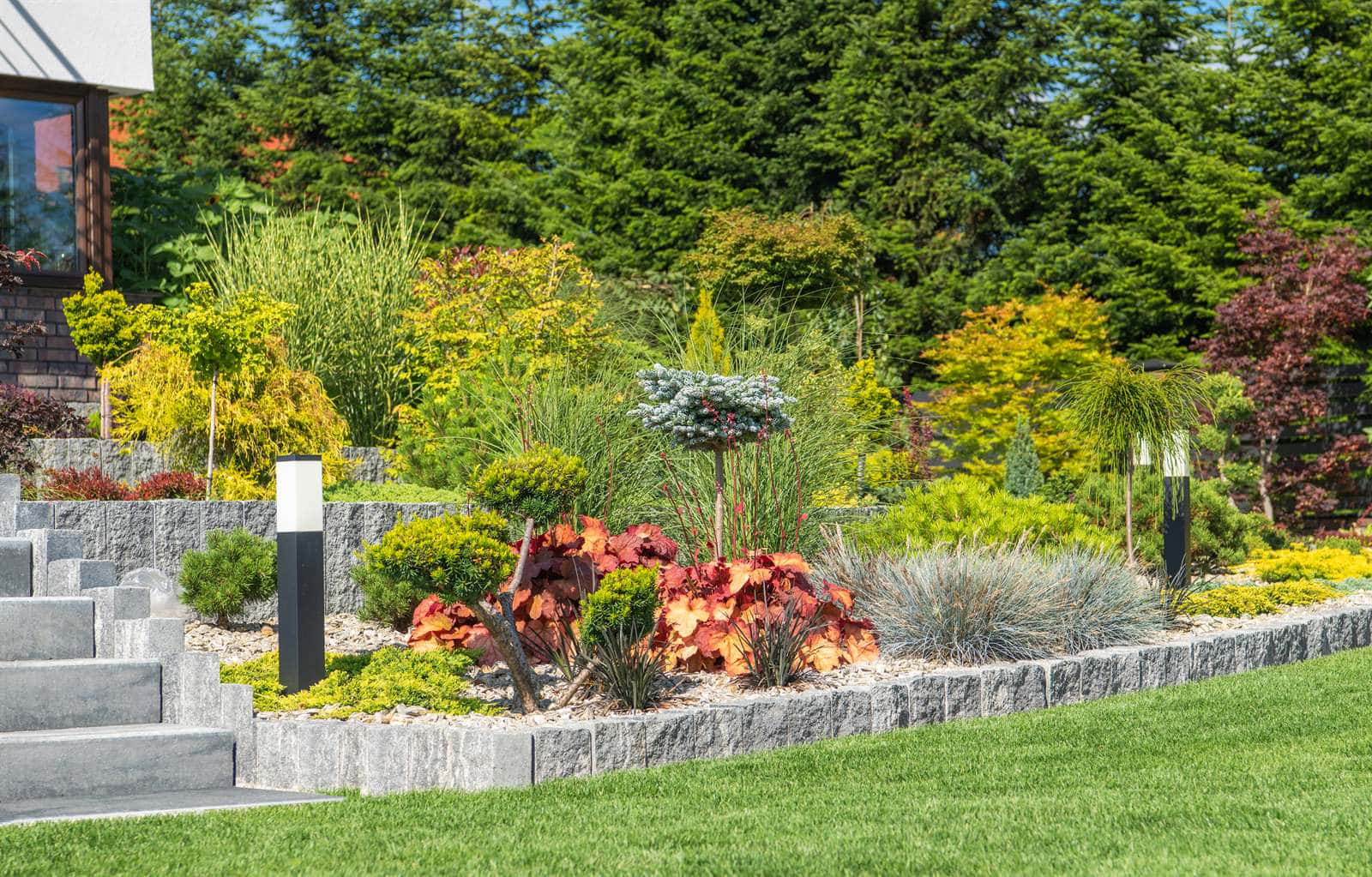 A planted rockery bed with ornamental grasses and a stone retaining wall